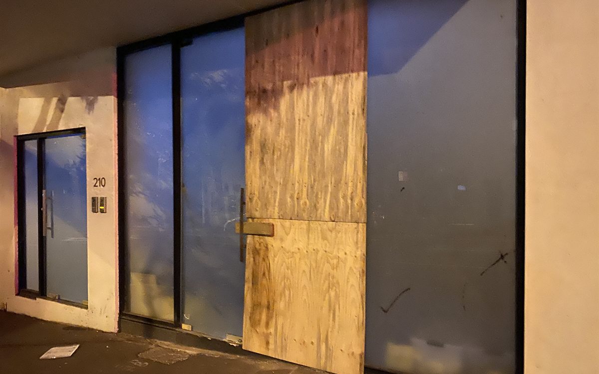 Emergency plywood board-up over broken shopfront glass in Northgate